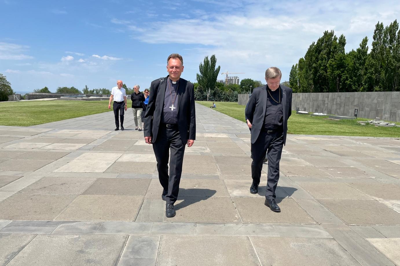 Die Erzbischöfe Stephan Burger und Herwig Gössl gehen gemeinsam mit den weiteren Mitgliedern der Delegation über die weite Esplanade des Hügels von Dzidzernagapert in Richtung des Heiligtums der Ewigkeit