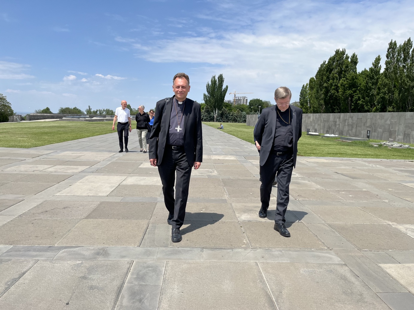 Die Erzbischöfe Stephan Burger und Herwig Gössl gehen gemeinsam mit den weiteren Mitgliedern der Delegation über die weite Esplanade des Hügels von Dzidzernagapert in Richtung des Heiligtums der Ewigkeit